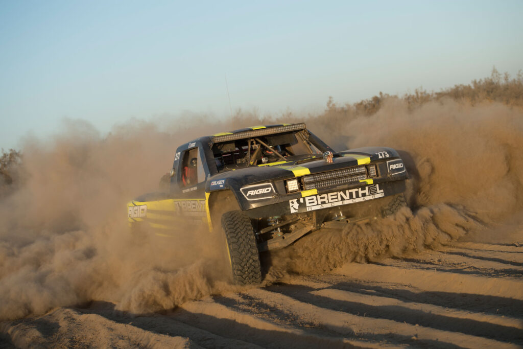 Brenthel Industries 6100 trophy truck in the 2016 Laughlin Desert Classic LDC race driving through sand and leaving behind a cloud of dust